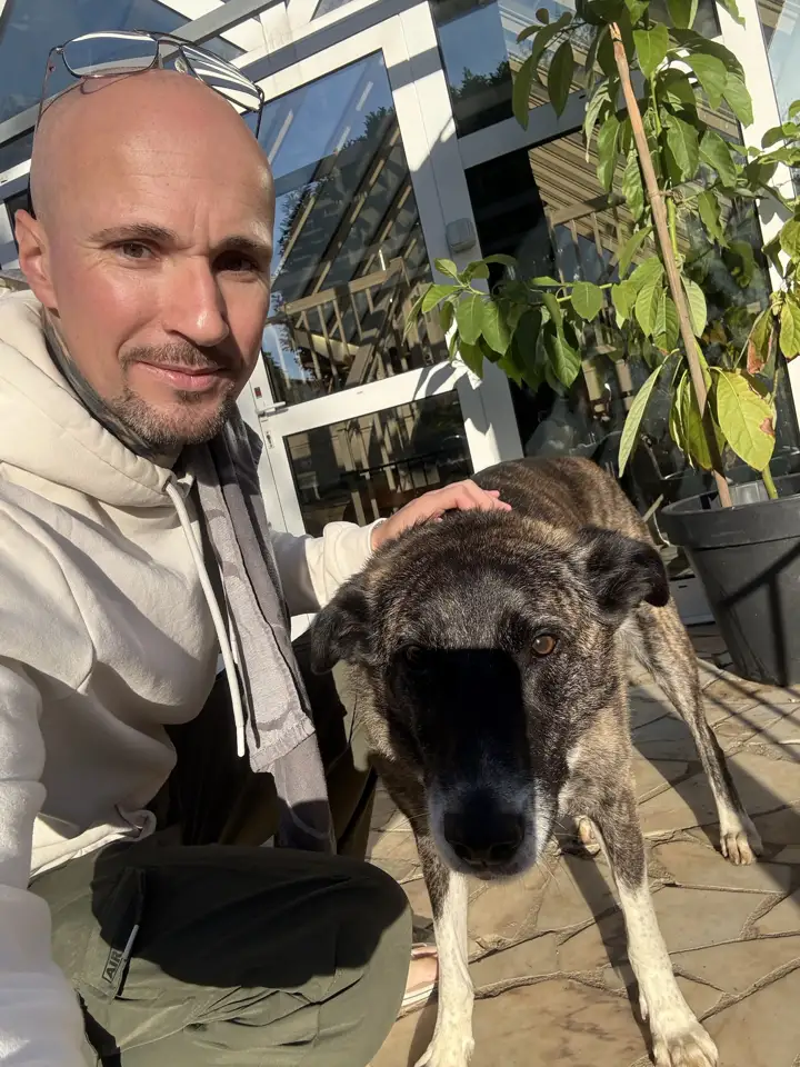 Damien en terrasse avec un chien bringé